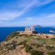 Greece Cape Sounio, Poseidon temple aerial drone view. Archaeological site of ancient greek temple ruins up on a hill, Athens Attica. Cloudy blue sky backgrpund, sunny day