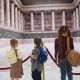 Three schoolkids with backpacks visiting modern museum